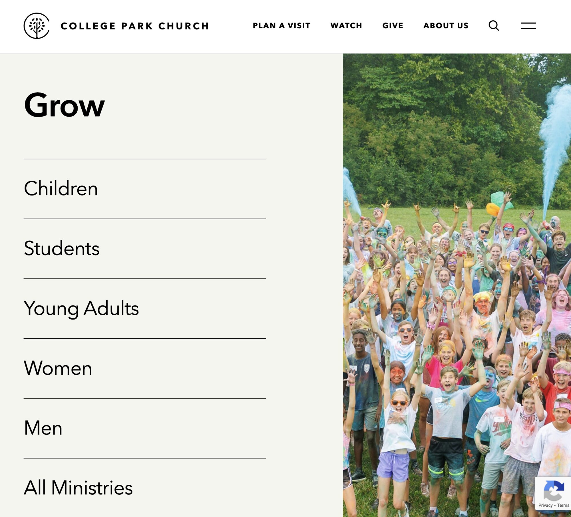A large group of children and adults, covered in colorful powder, smile and cheer outdoors on a grassy field at what appears to be a community or church event. The left side displays navigation options for the churchs ministries.