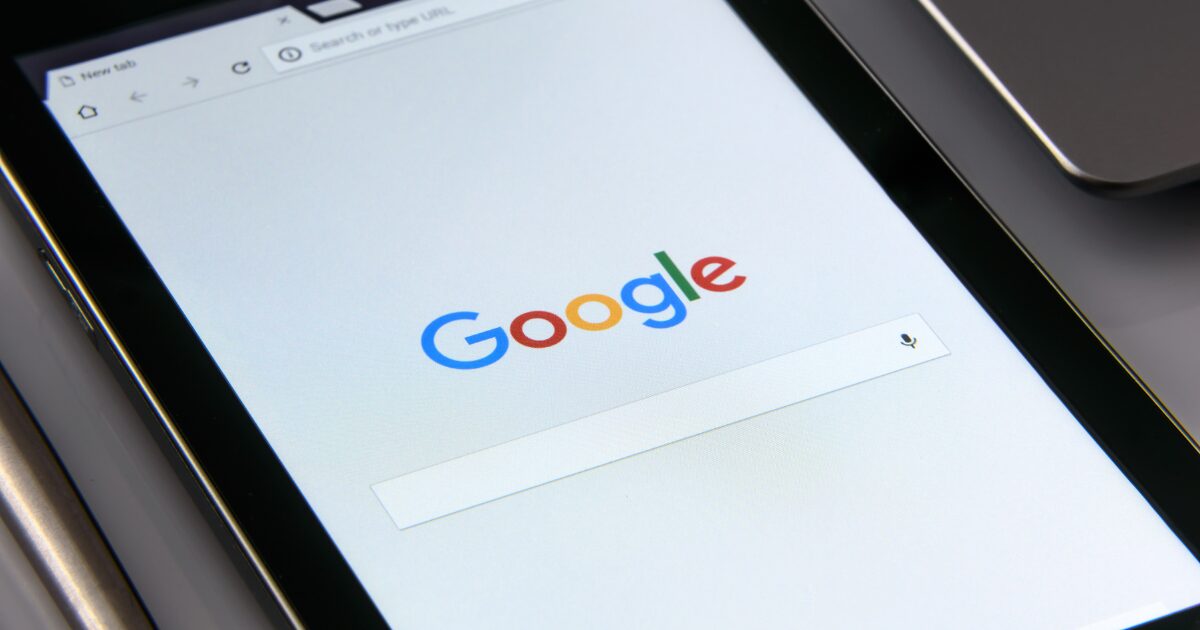 A tablet screen displays the Google homepage with the search bar and microphone icon visible, highlighting how users can easily begin their marketing research online.